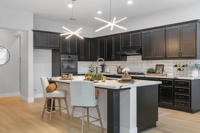 a kitchen with a sink a stove a refrigerator cabinets and dining table