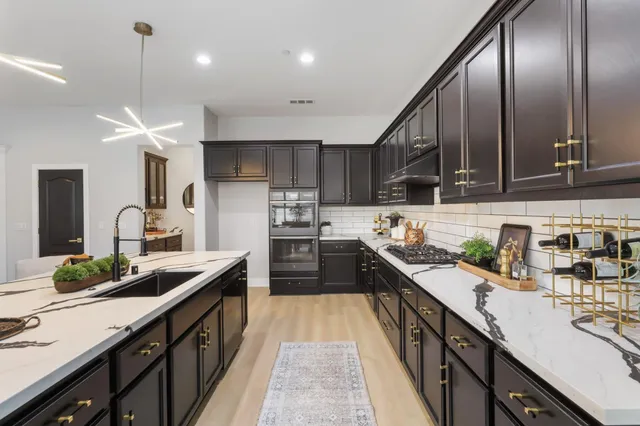 a kitchen with kitchen island granite countertop lots of counter top space a sink and appliances