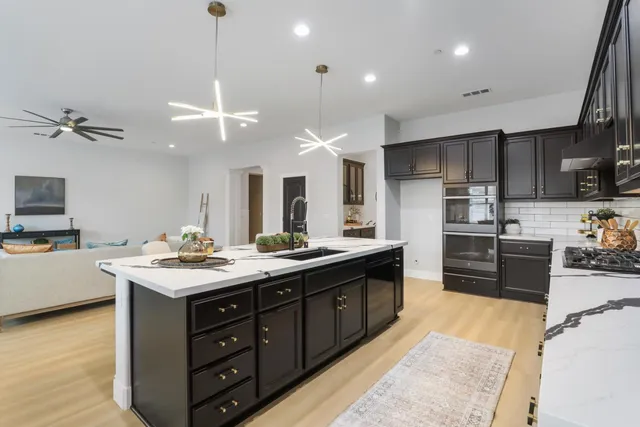 a kitchen with stainless steel appliances granite countertop a sink a stove and a wooden floors