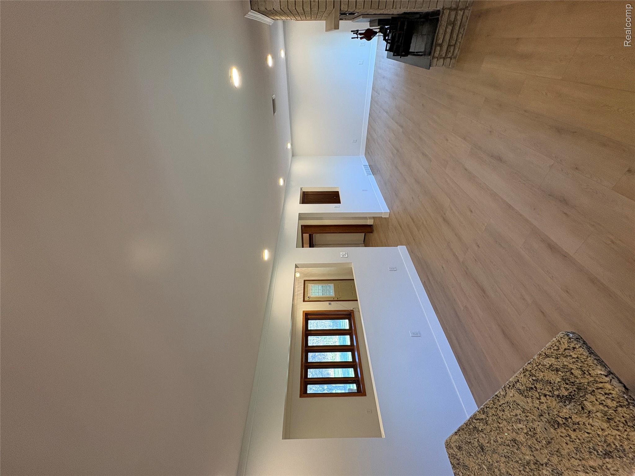 11779 Dunn Road Memphis, MI 48041 - Photo 19 of 44 Spacious living area featuring wood-finish flooring, recessed lighting, and a brick fireplace with a stone hearth