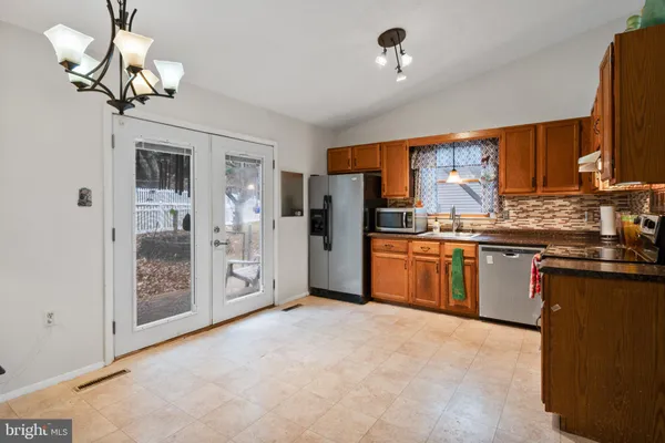 a kitchen with stainless steel appliances granite countertop a refrigerator a sink dishwasher a stove and a refrigerator with wooden floor