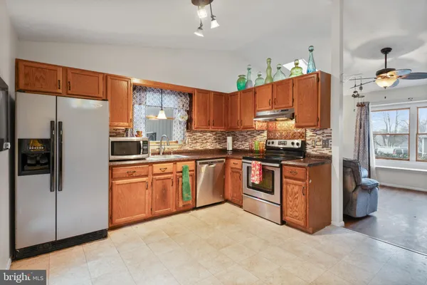 a kitchen with stainless steel appliances granite countertop a refrigerator a sink dishwasher a stove with wooden cabinets and floor