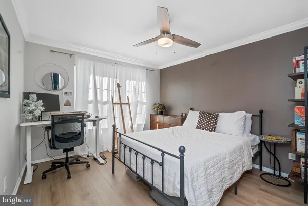 a bedroom with a bed a desk and chair with wooden floor