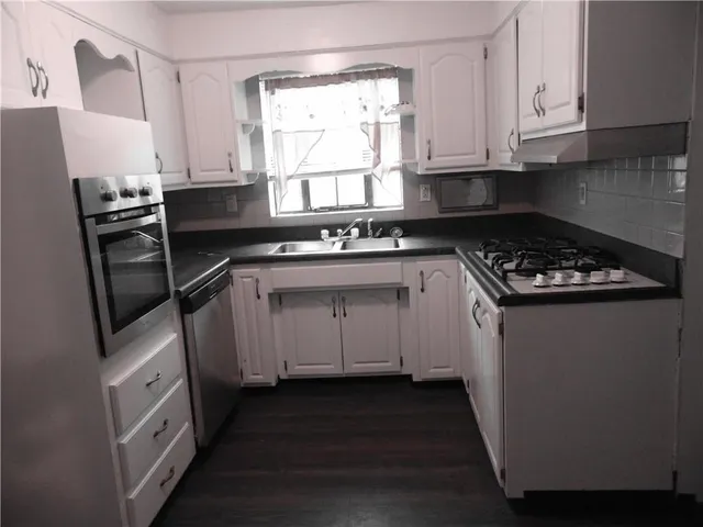 a kitchen with white cabinets sink and appliances