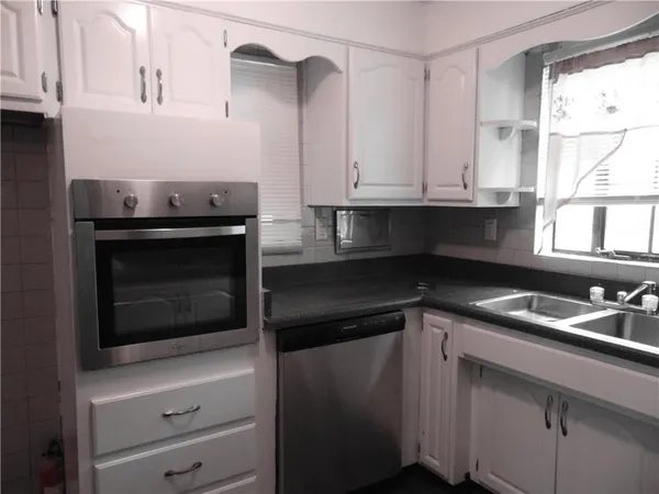 a kitchen with granite countertop white cabinets and appliances