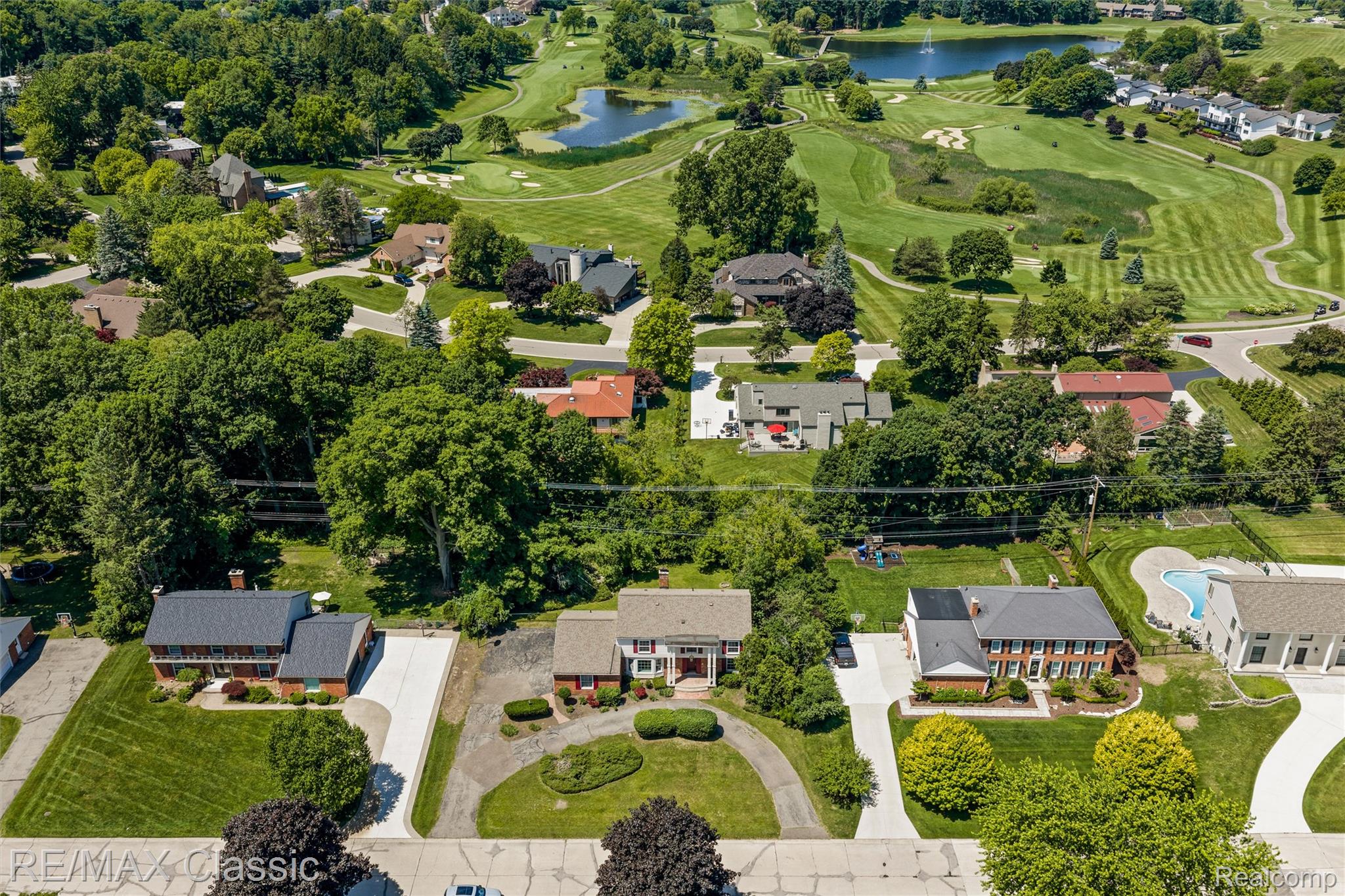 4268 Covered Bridge Road Bloomfield Hills, MI 48302 - Photo 34 of 35 Elevated aerial perspective showcasing a residential neighborhood with mature trees, expansive green lawns, and a golf course featuring multiple water features