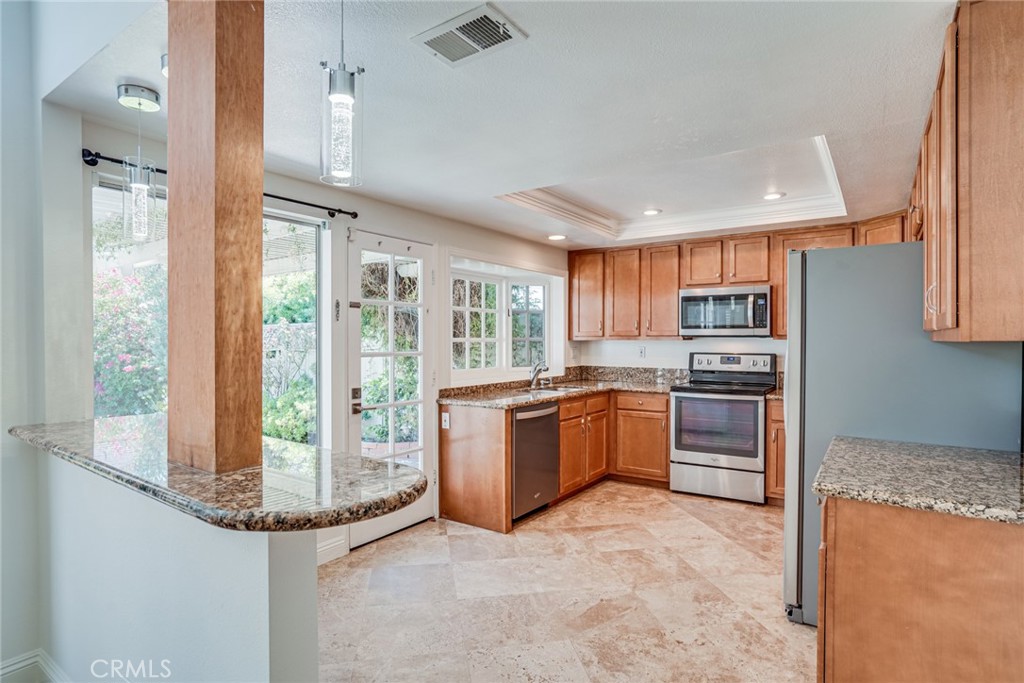 49 East Yale Loop, Unit 26 Irvine, CA 92604 - Photo 11 of 63 a kitchen with stainless steel appliances granite countertop a refrigerator and a stove top oven
