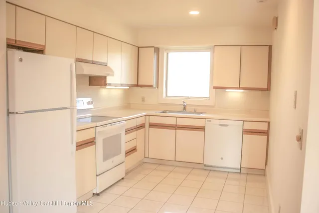 a kitchen with a refrigerator a sink and dishwasher with white cabinets
