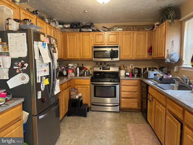 a kitchen with stainless steel appliances a stove a sink and a refrigerator
