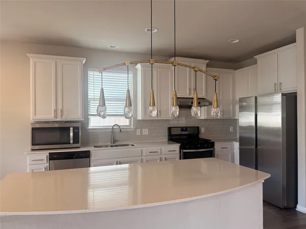a kitchen with kitchen island a counter space a sink a refrigerator and cabinets