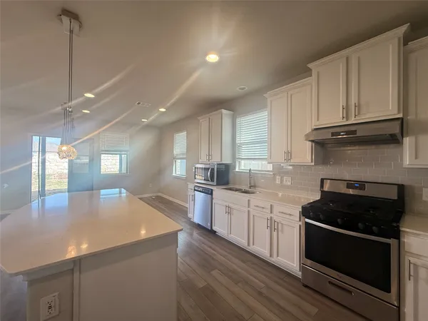 a kitchen with stainless steel appliances kitchen island granite countertop a stove a sink and a refrigerator