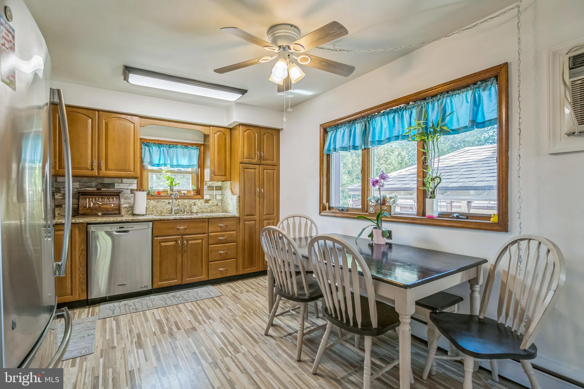361 Amosland Road Holmes, PA 19043 - Photo 14 of 30 a kitchen with granite countertop a stove a sink dishwasher a dining table and chairs with wooden floor