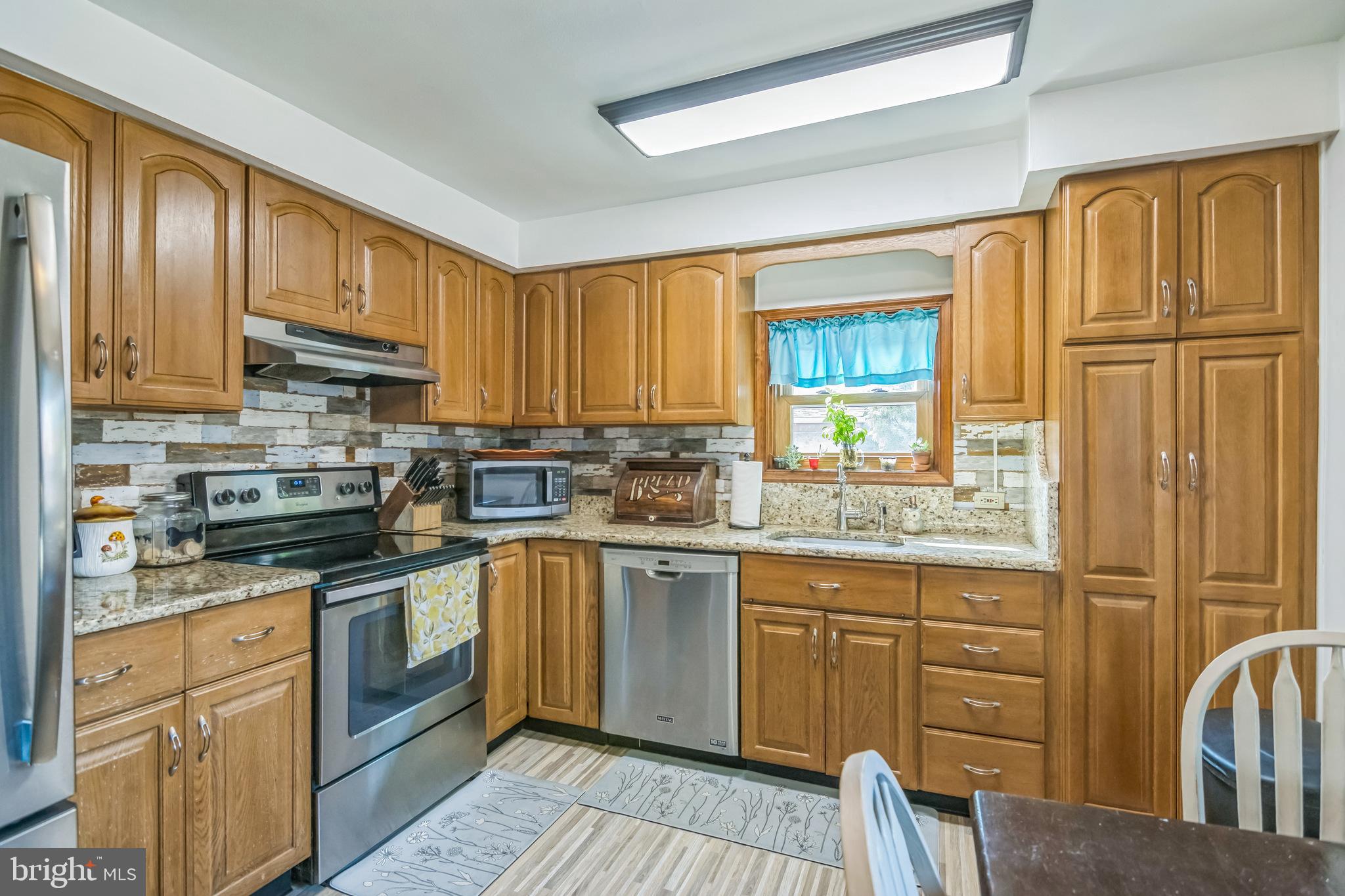 361 Amosland Road Holmes, PA 19043 - Photo 15 of 30 a kitchen with granite countertop wooden cabinets stainless steel appliances a sink and a window