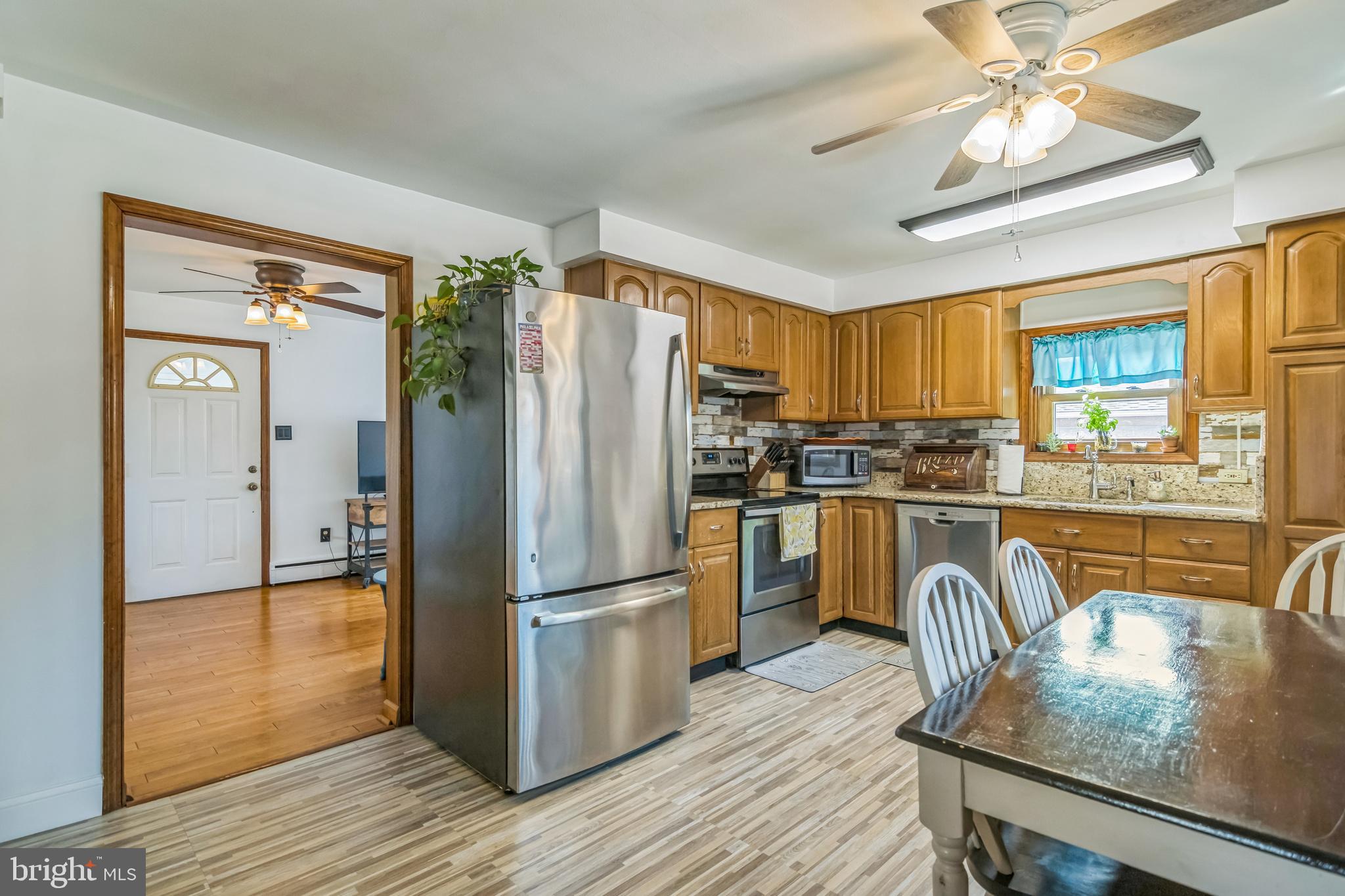 361 Amosland Road Holmes, PA 19043 - Photo 17 of 30 a kitchen with granite countertop a refrigerator a stove a sink dishwasher a dining table and chairs with wooden floor