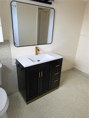 a bathroom with a sink vanity mirror and toilet