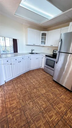a kitchen with granite countertop a stove a sink and a refrigerator