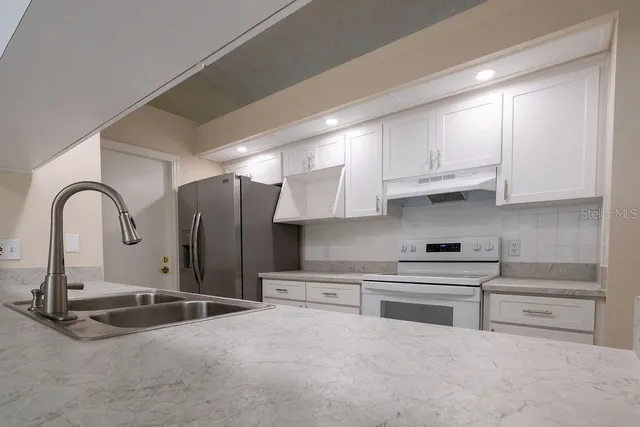 a kitchen with stainless steel appliances granite countertop a stove a sink and a refrigerator