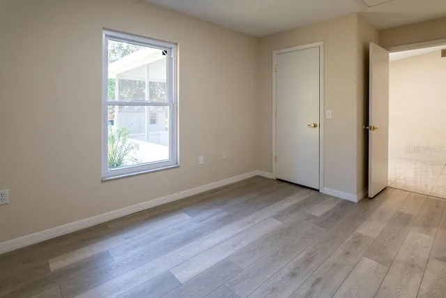 an empty room with wooden floor and windows