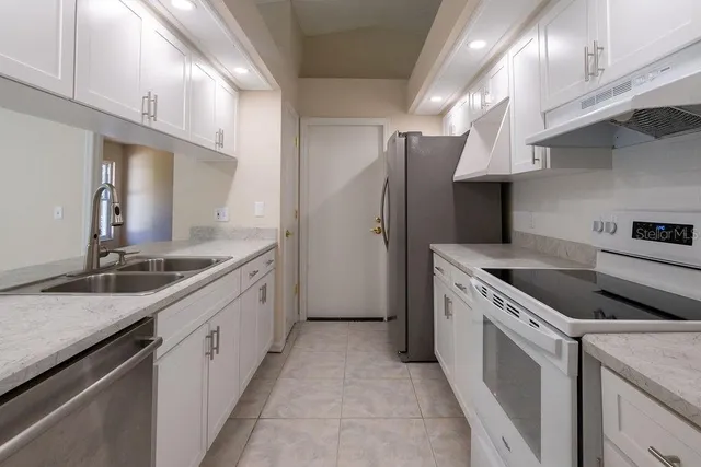 a kitchen with stainless steel appliances granite countertop a sink and a refrigerator