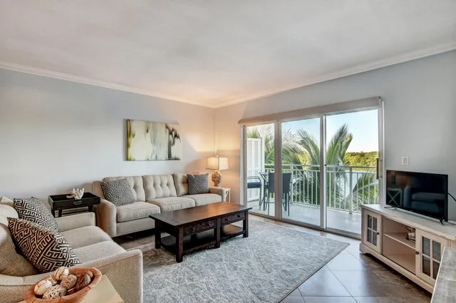 a living room with furniture a flat screen tv and a floor to ceiling window