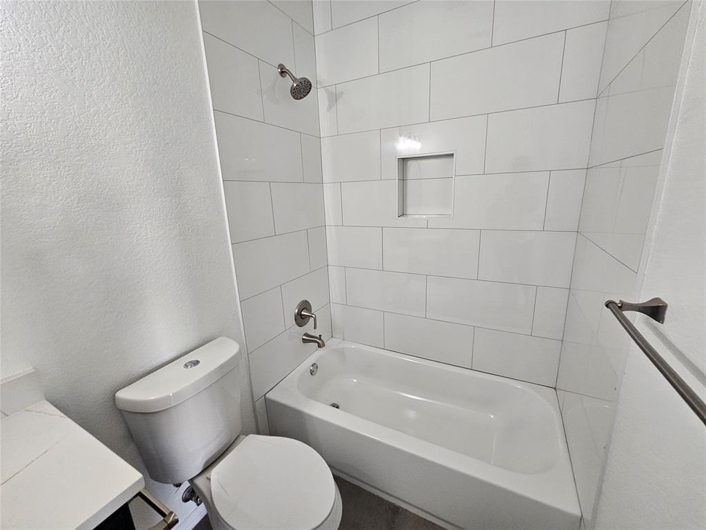 207 Starr Street Dallas, TX 75203 - Photo 17 of 28 Full bathroom featuring a textured wall, shower combination, and vanity