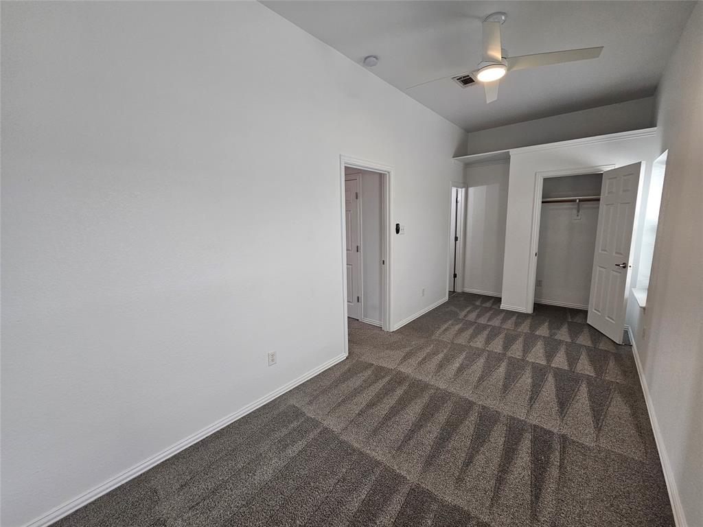 207 Starr Street Dallas, TX 75203 - Photo 21 of 28 Unfurnished bedroom with a ceiling fan, a closet, and dark colored carpet
