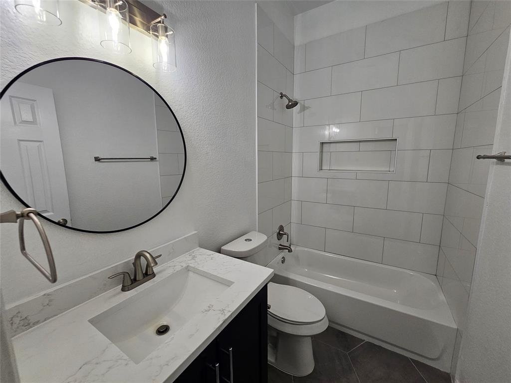 207 Starr Street Dallas, TX 75203 - Photo 22 of 28 Bathroom with a textured wall, shower combination, vanity, and dark tile patterned floors