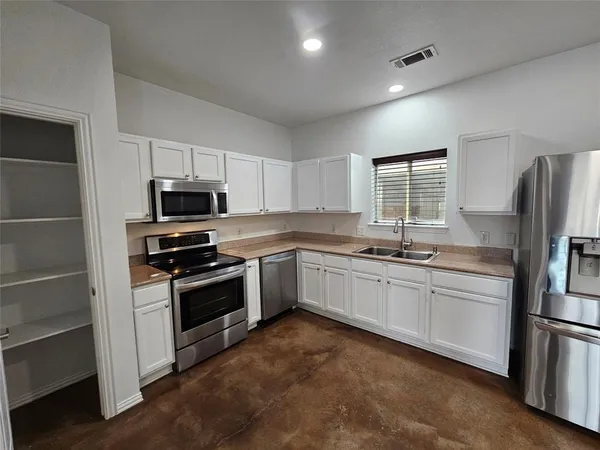 a kitchen with granite countertop a refrigerator stove and microwave