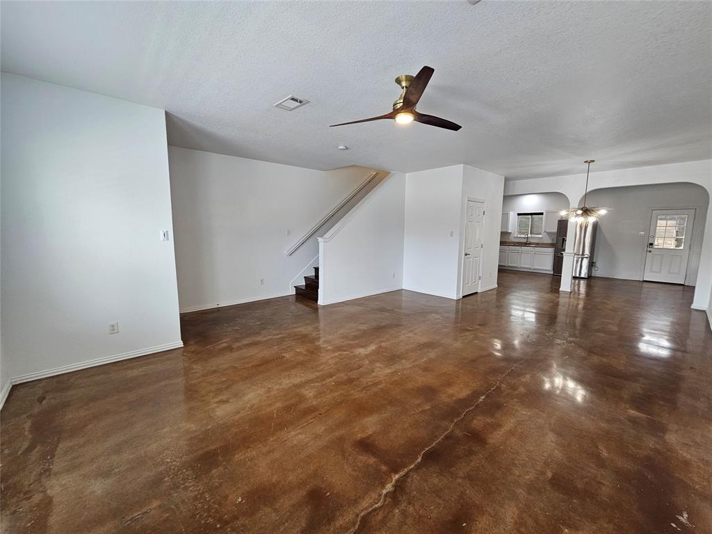 207 Starr Street Dallas, TX 75203 - Photo 7 of 28 Unfurnished living room with concrete floors, a ceiling fan, arched walkways, and a textured ceiling