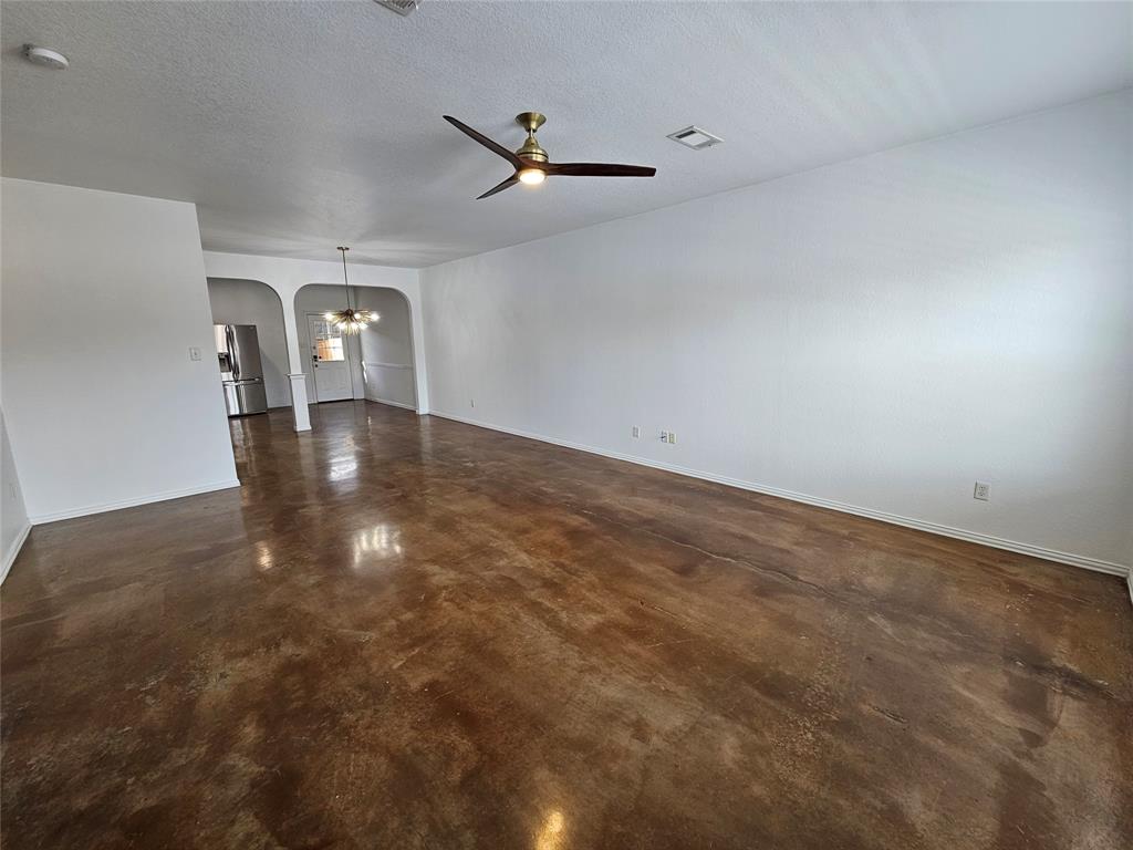 207 Starr Street Dallas, TX 75203 - Photo 8 of 28 Empty room featuring arched walkways, concrete flooring, ceiling fan, and a textured ceiling