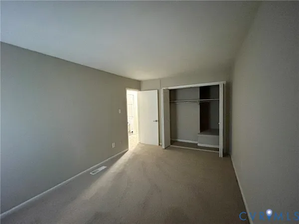 a view of an empty room with closet and entryway