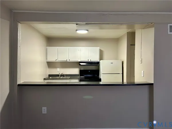 a view of kitchen with stainless steel appliances granite countertop white cabinets and a refrigerator