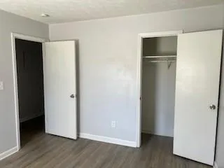 a view of an empty room with wooden floor and closet