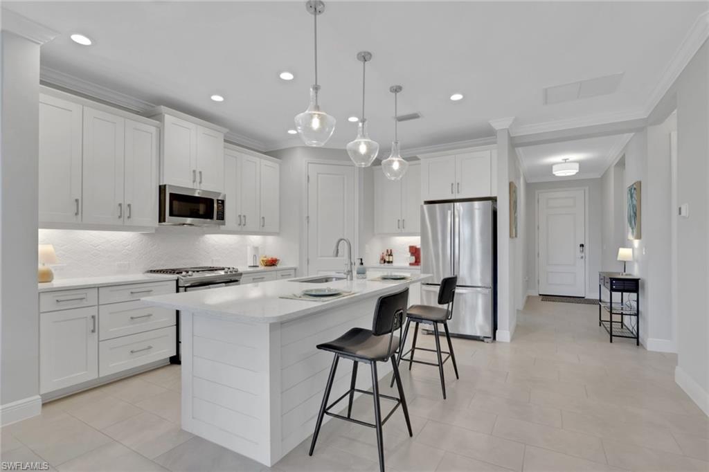 2194 Marquesa Circle Naples, FL 34112 - Photo 5 of 38 a kitchen with stainless steel appliances kitchen island a stove a sink a refrigerator and a refrigerator with wooden floor