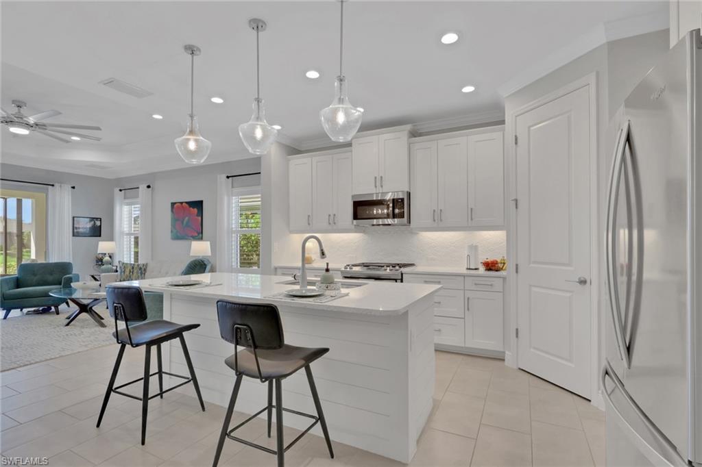 2194 Marquesa Circle Naples, FL 34112 - Photo 6 of 38 a kitchen with stainless steel appliances kitchen island granite countertop a refrigerator a stove a sink and white cabinets with wooden floor