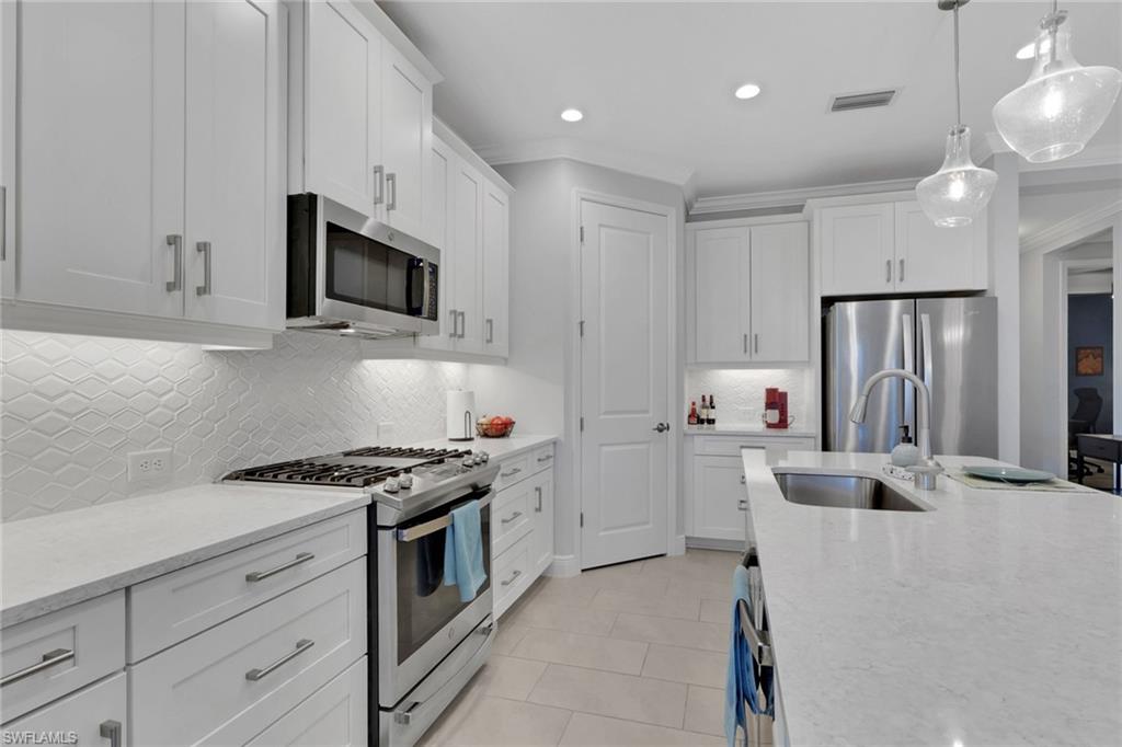 2194 Marquesa Circle Naples, FL 34112 - Photo 7 of 38 a kitchen with granite countertop a sink stainless steel appliances and white cabinets