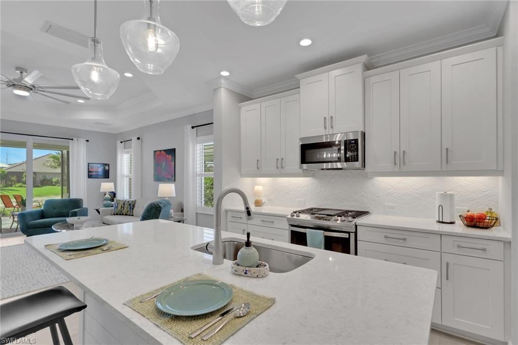 2194 Marquesa Circle Naples, FL 34112 - Photo 8 of 38 a kitchen with a sink a microwave a stove and white cabinets