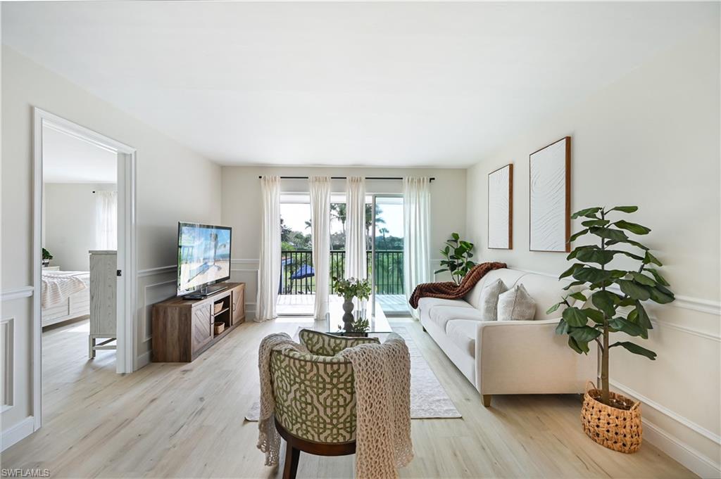 190 Pebble Beach Boulevard, Unit 202 Naples, FL 34113 - Photo 2 of 36 a living room with furniture and a flat screen tv