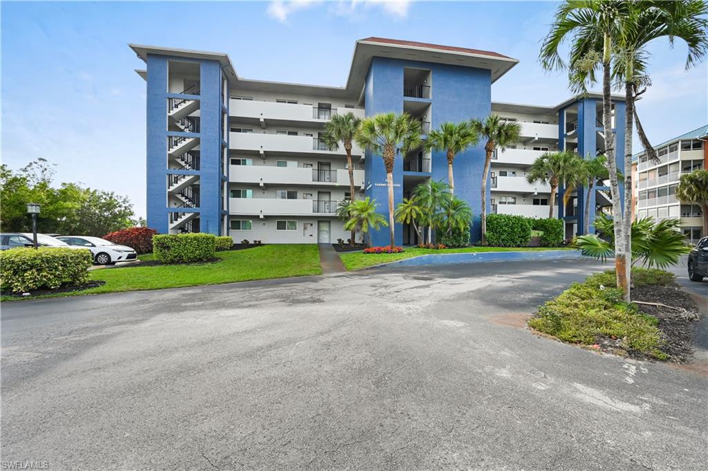 190 Pebble Beach Boulevard, Unit 202 Naples, FL 34113 - Photo 32 of 36 a front view of a building with garden and trees