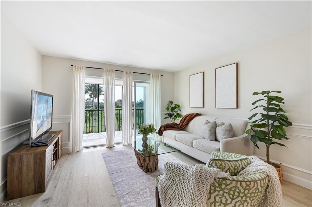 190 Pebble Beach Boulevard, Unit 202 Naples, FL 34113 - Photo 5 of 36 a living room with furniture a large window and a flat screen tv
