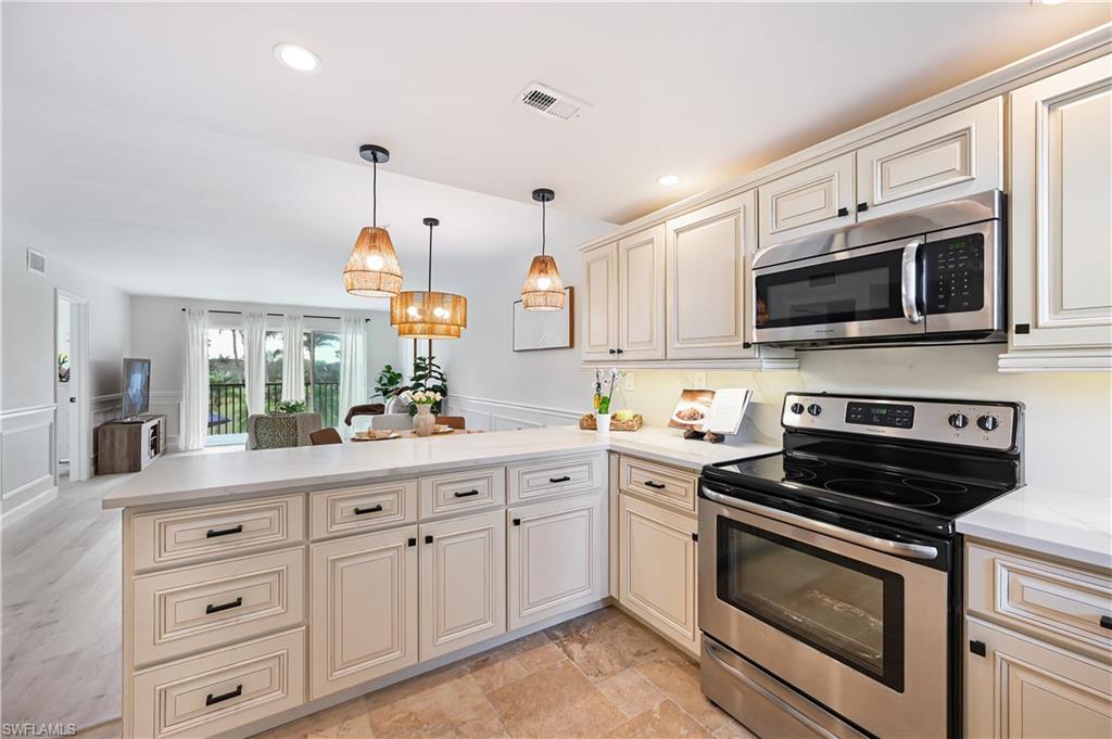 190 Pebble Beach Boulevard, Unit 202 Naples, FL 34113 - Photo 10 of 36 a kitchen with white cabinets and stainless steel appliances
