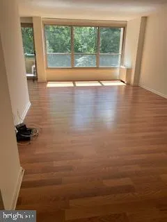 a view of an empty room with wooden floor and a window