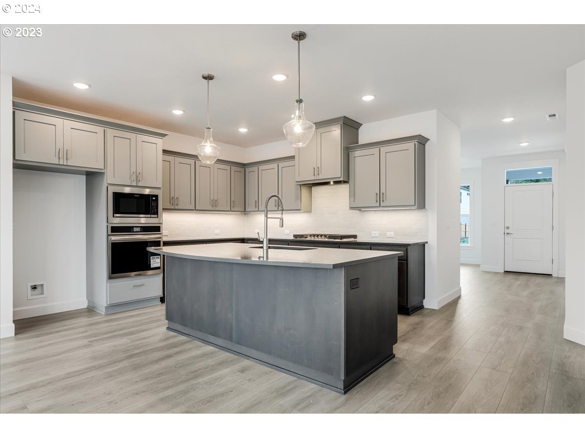 17127 Southwest Kalapuya Lane Sherwood, OR 97140 - Photo 8 of 18 a large kitchen with stainless steel appliances kitchen island granite countertop a large counter top and a stove top oven
