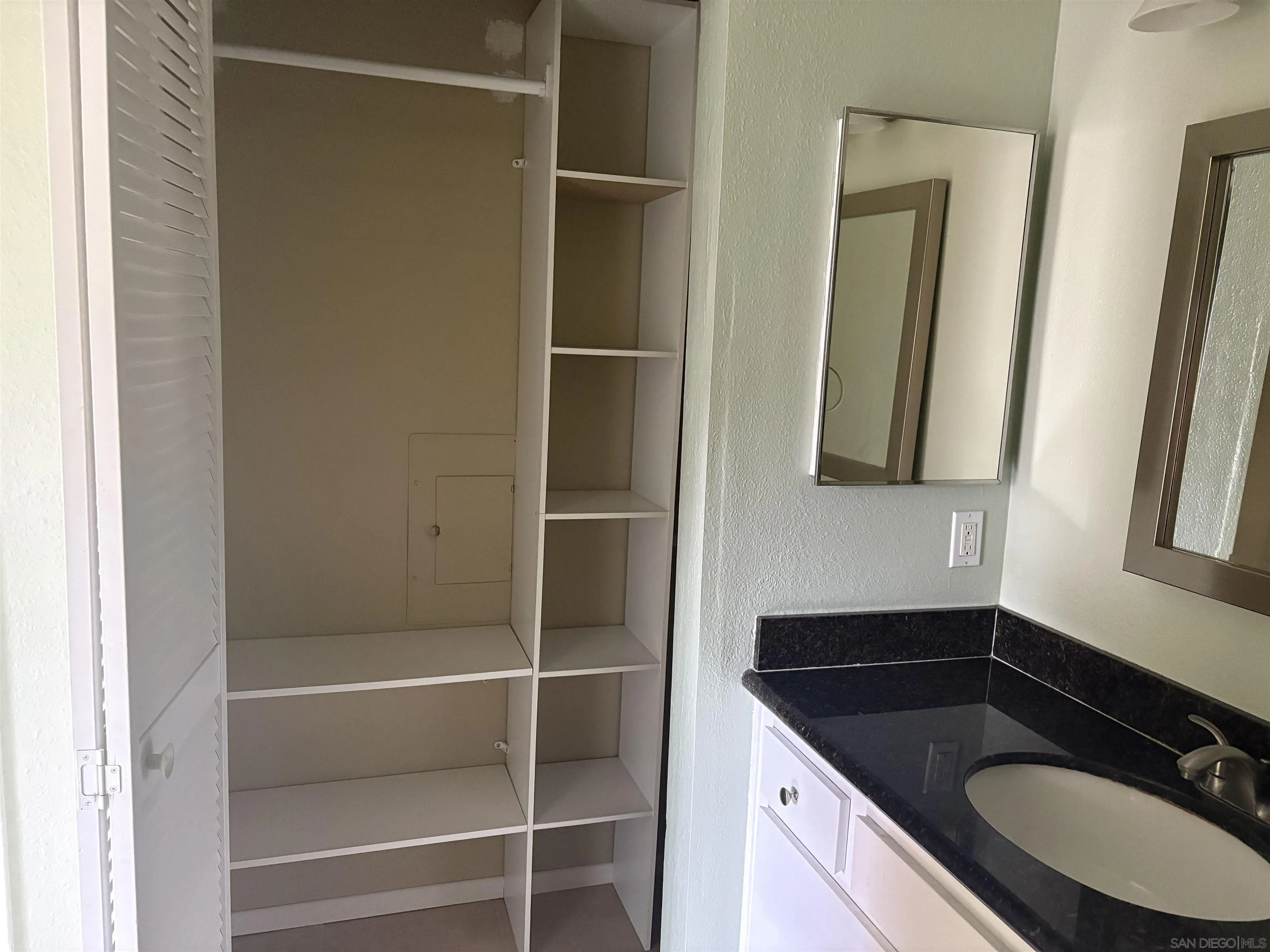 5962 Rancho Mission Road, Unit 222 San Diego, CA 92108 - Photo 32 of 42 a bathroom with a granite countertop sink and a mirror