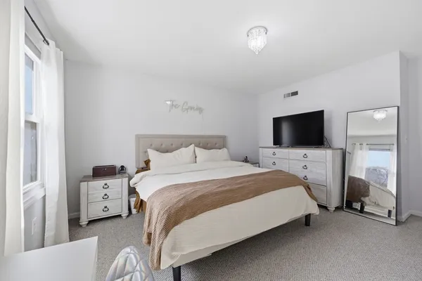 a bedroom with a bed and a flat tv screen on wall