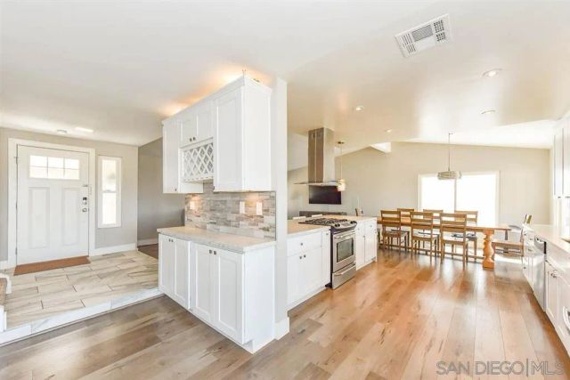 a large kitchen with a lot of counter space and wooden floor