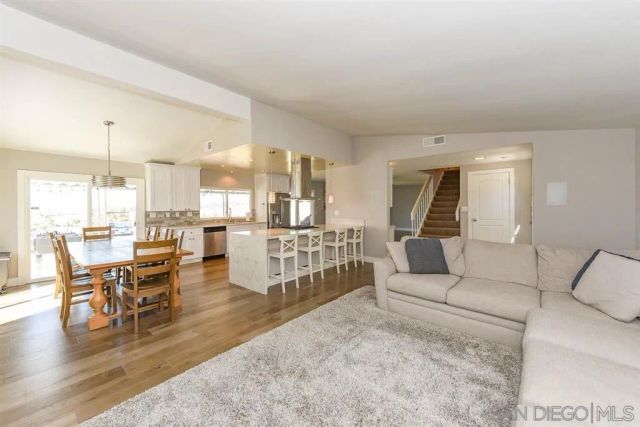 a living room with furniture and a dining table with wooden floor