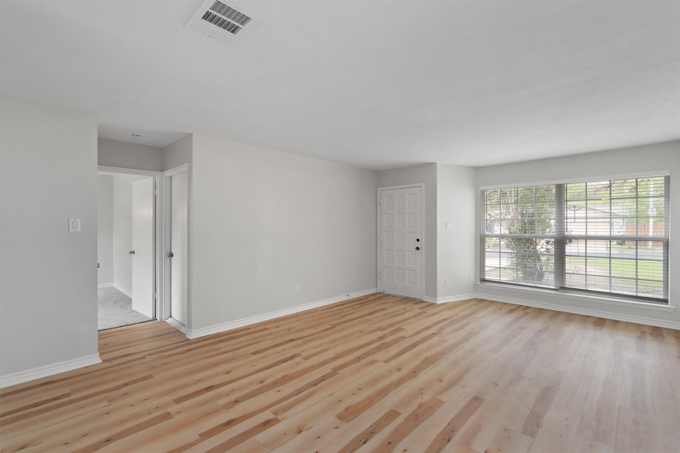 2532 Chaparral Trail Austin, TX 78744 - Photo 4 of 27 a view of an empty room with wooden floor and a window