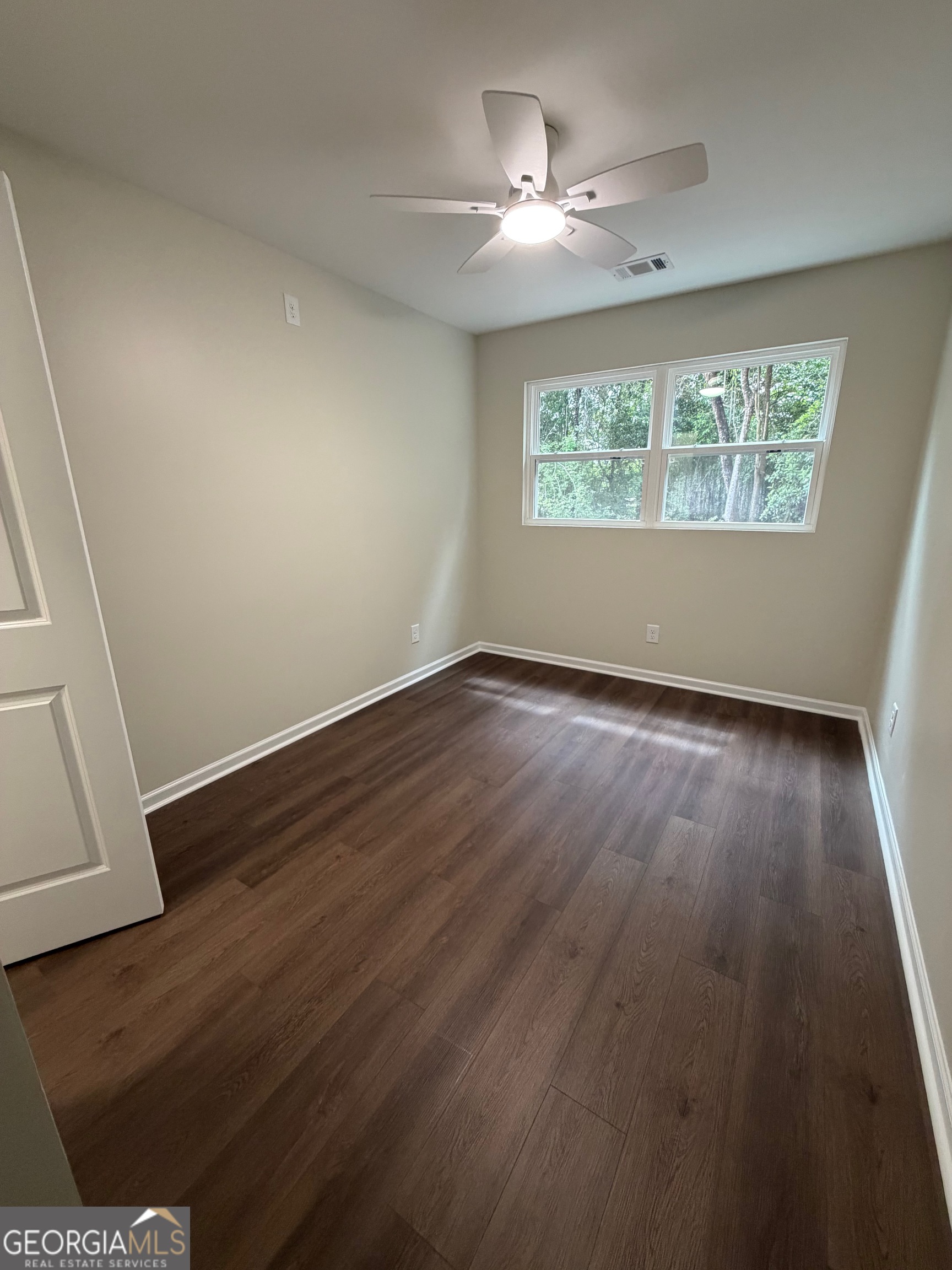 2809 Jones Road Sandersville, GA 31082 - Photo 23 of 31 an empty room with wooden floor chandelier fan and windows