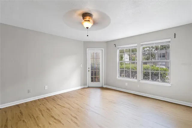 an empty room with wooden floor and windows